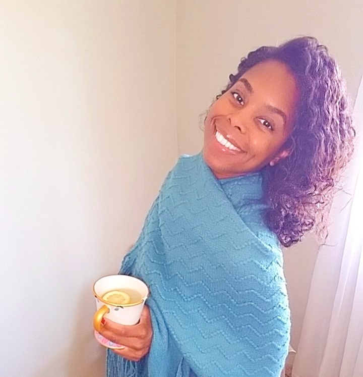 beautiful black woman smiling and holding beauty and the beast tea cup with lemon water inside.